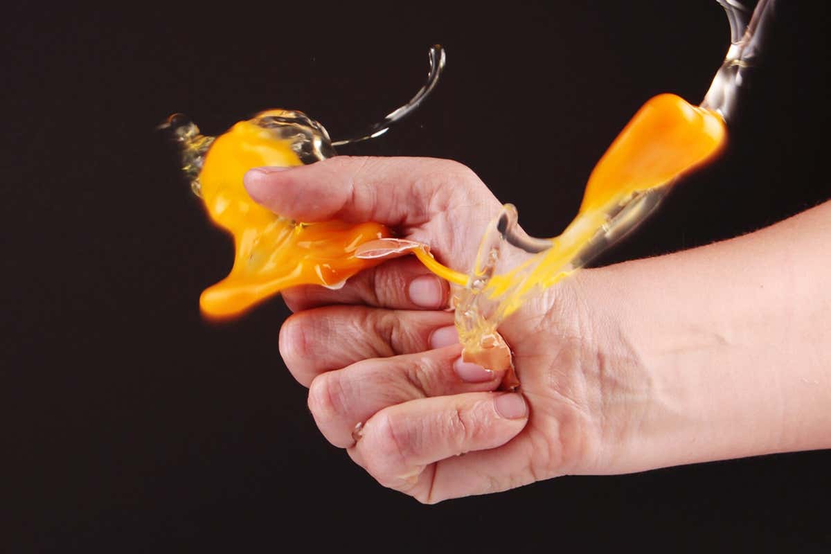 Hand crushing a raw egg