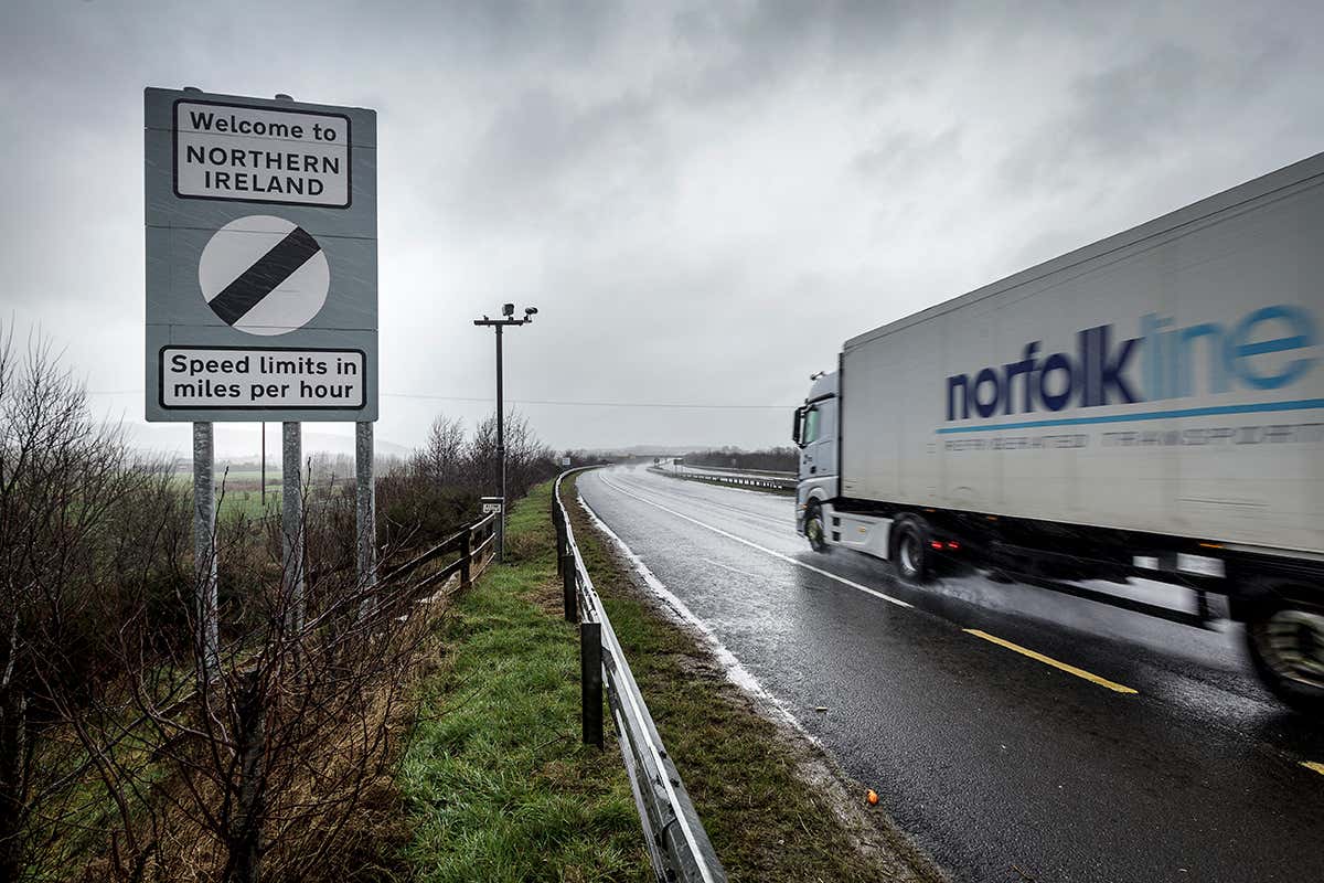 Lorry heads up road past sign saying 