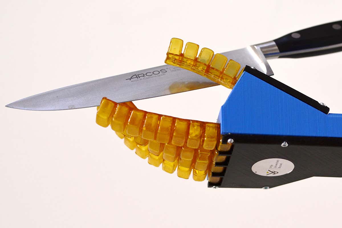 A robotic hand with jelly-like fingers holds a kitchen knife