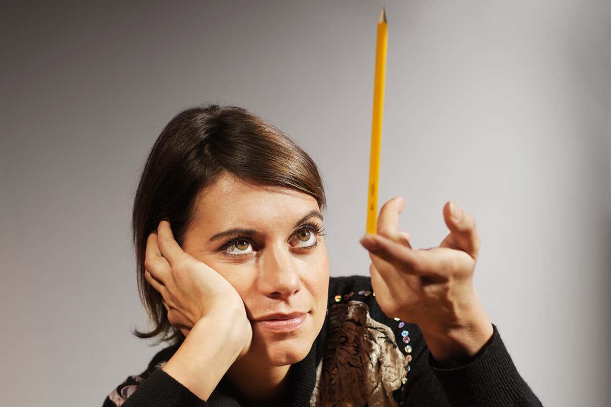 A woman balancing a pencil on her finger