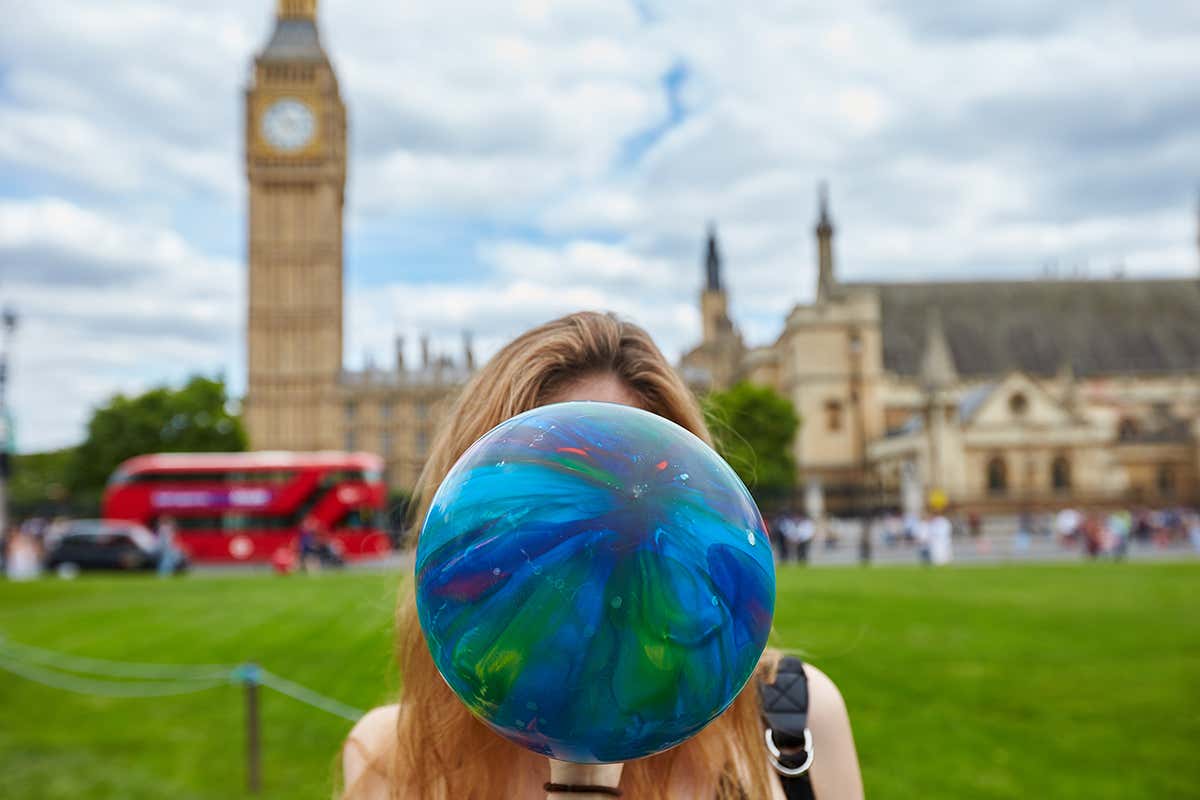 person inhaling a balloon in front of houses of parliament
