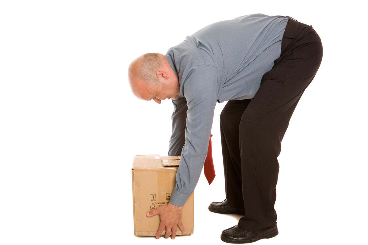 A man bending over to pick up the box