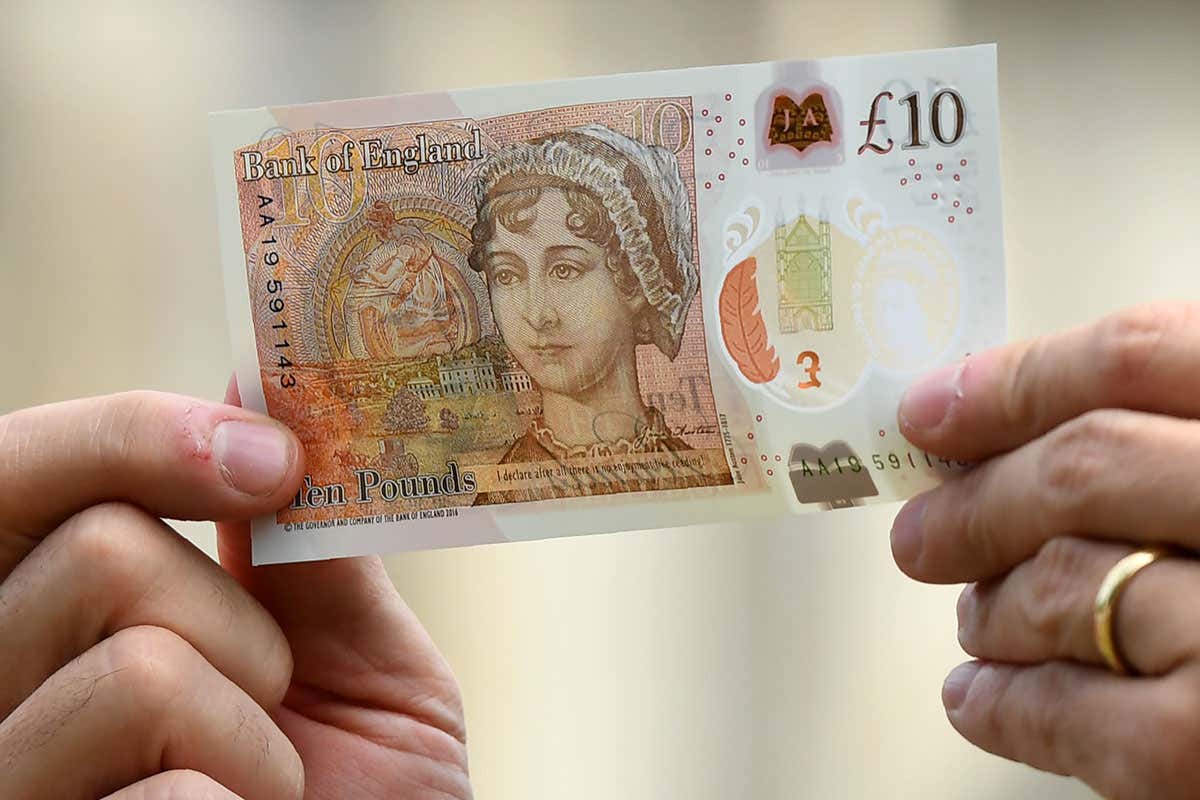 Hands holding new £10 banknote