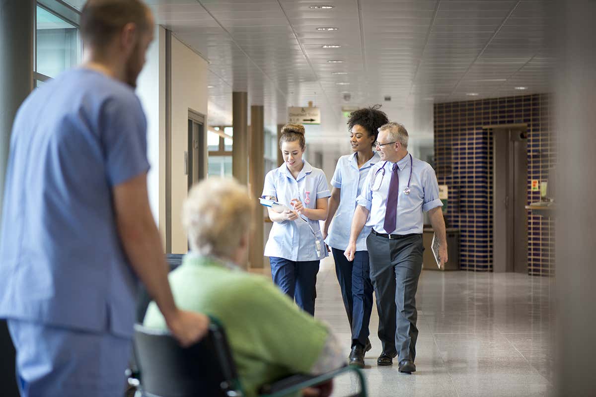 Hospital staff talk to each other while walking down a corridor