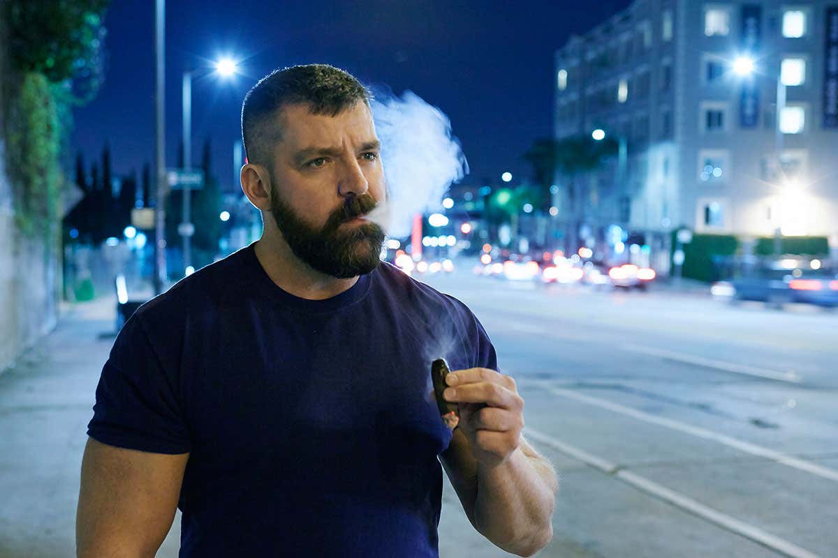 Man smoking cigar by road