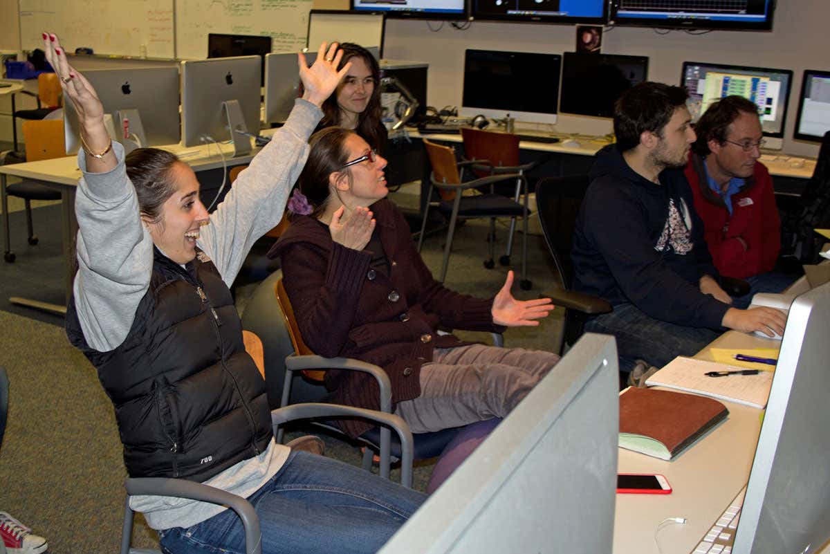 Researchers sitting at their desks celebrate a positive result