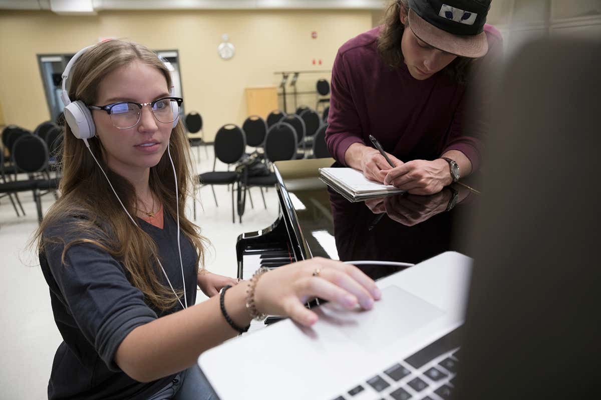 Woman wearing headphones uses laptop trackpad