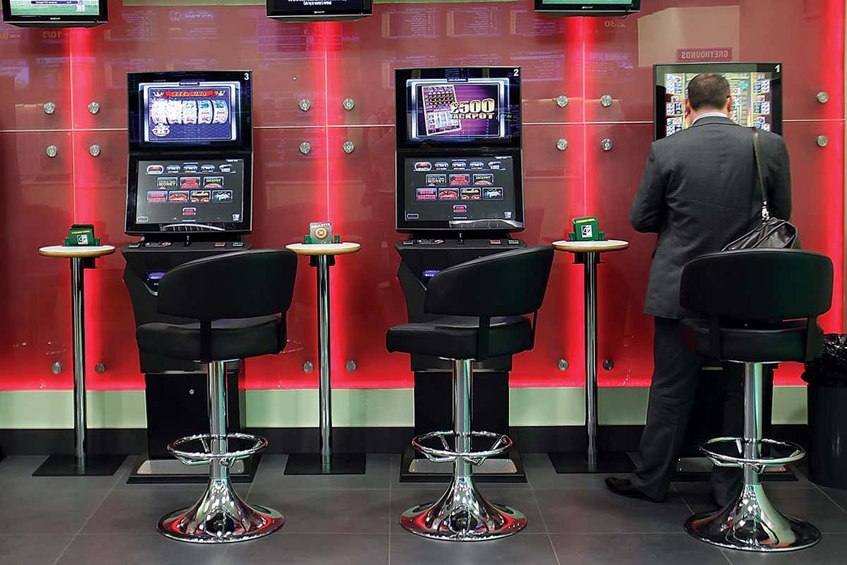 A row of three fixed-odds betting machines with a man sat at the machine on the right