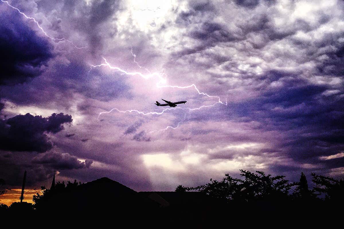 purple sky with lightning and a plane in the background