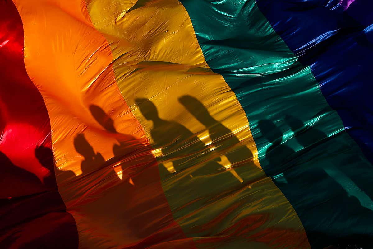 shadows in front of a rainbow flag