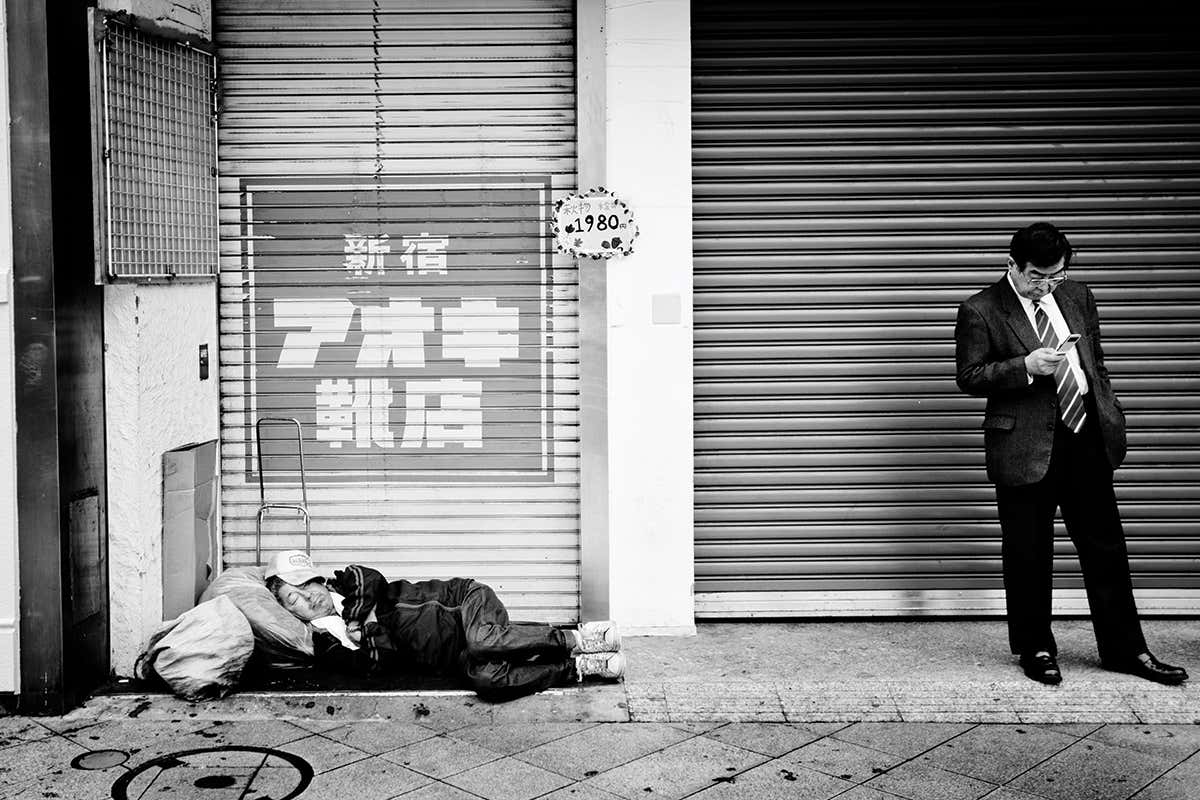 Man sleeping on street and man on phone