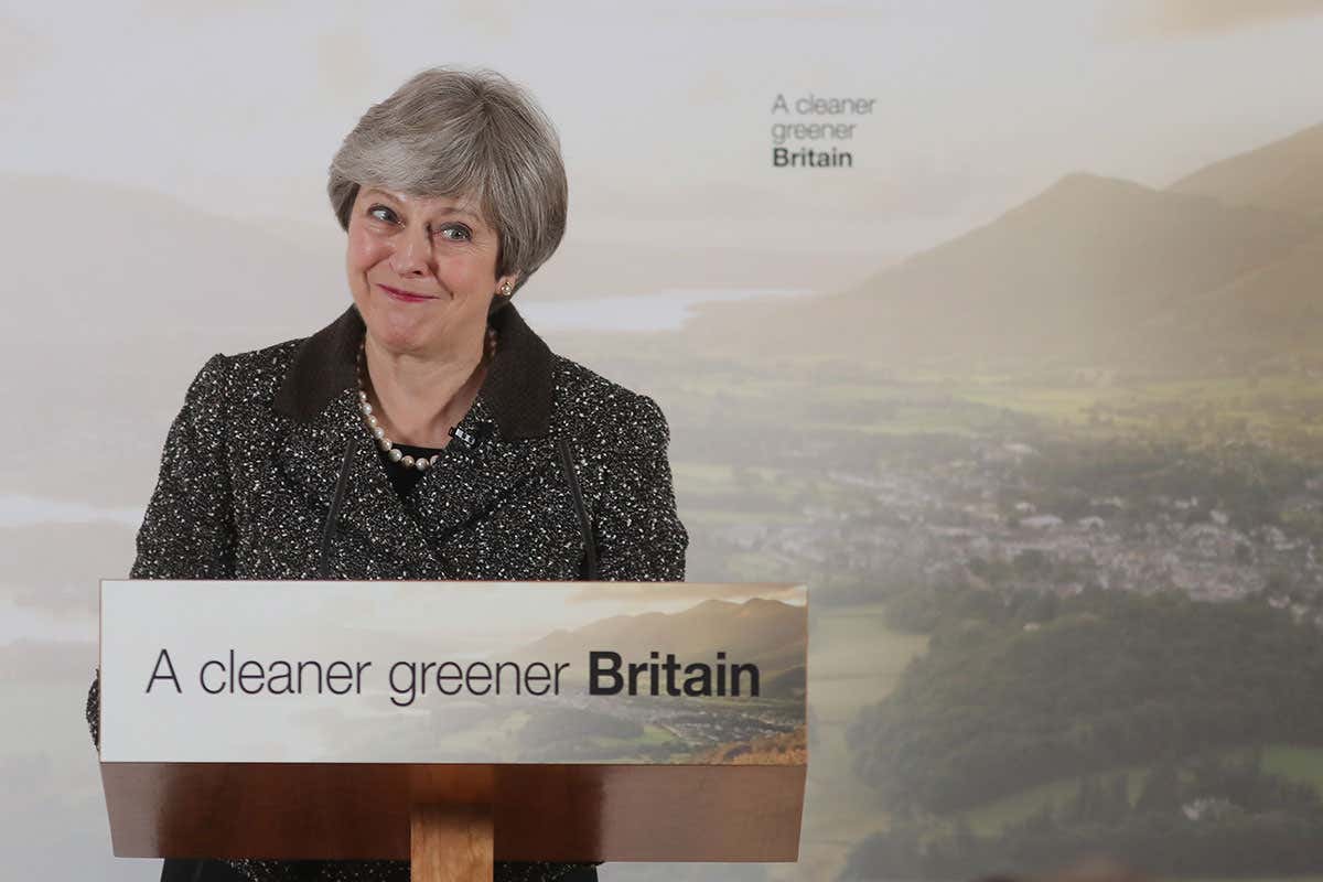Smiling Theresa May at a podium that says