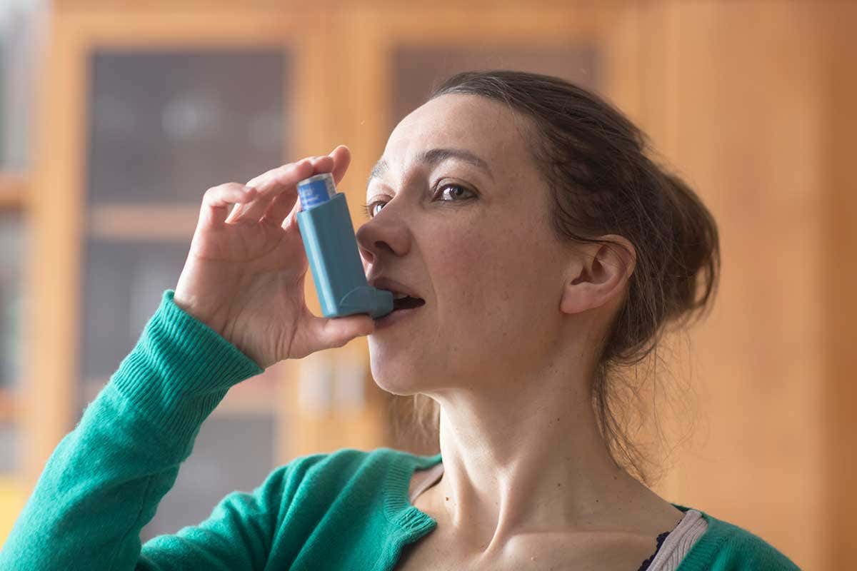 A woman using an asthma inhaler