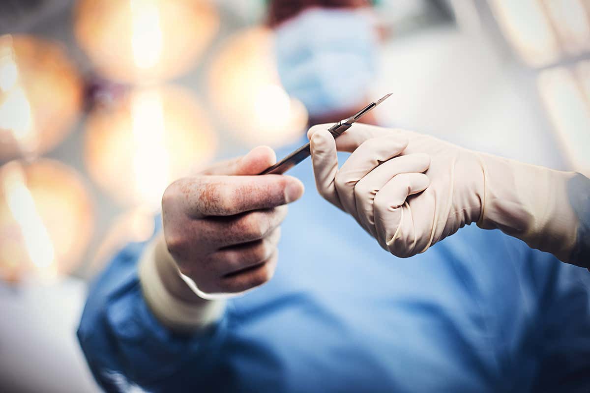 A surgeon passing a surgical implement to a colleague