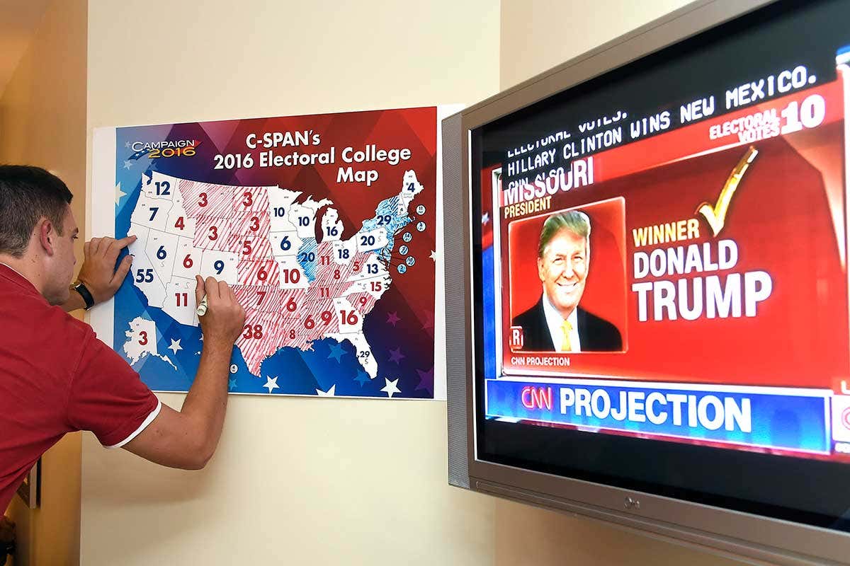 A person watching the 2016 US election coverage on TV and marking the results on a map
