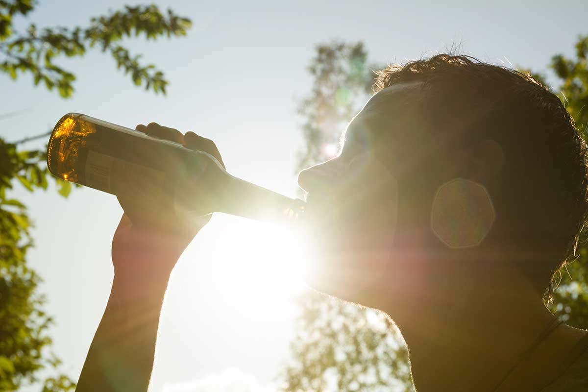A man drinking out of a bottle of alcohol