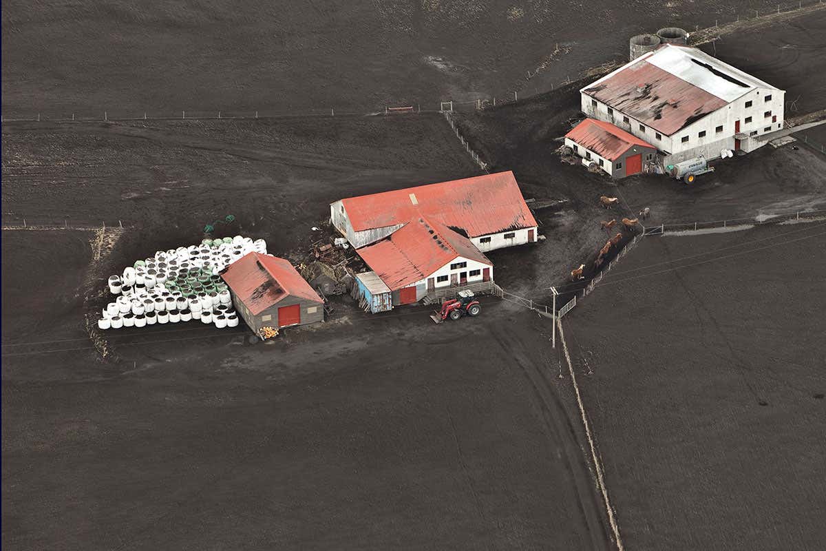 Farm buildings surrounded by dark-coloured material