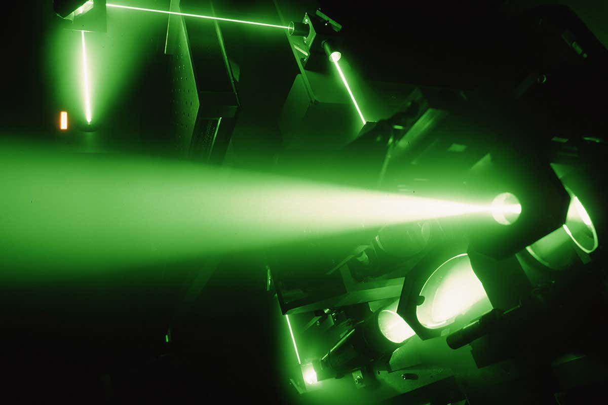 Green laser beam in darkness passing through optical equipment