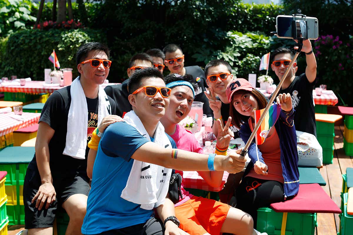 A group of young people in Shanghai holding a rainbow flag take a selfie