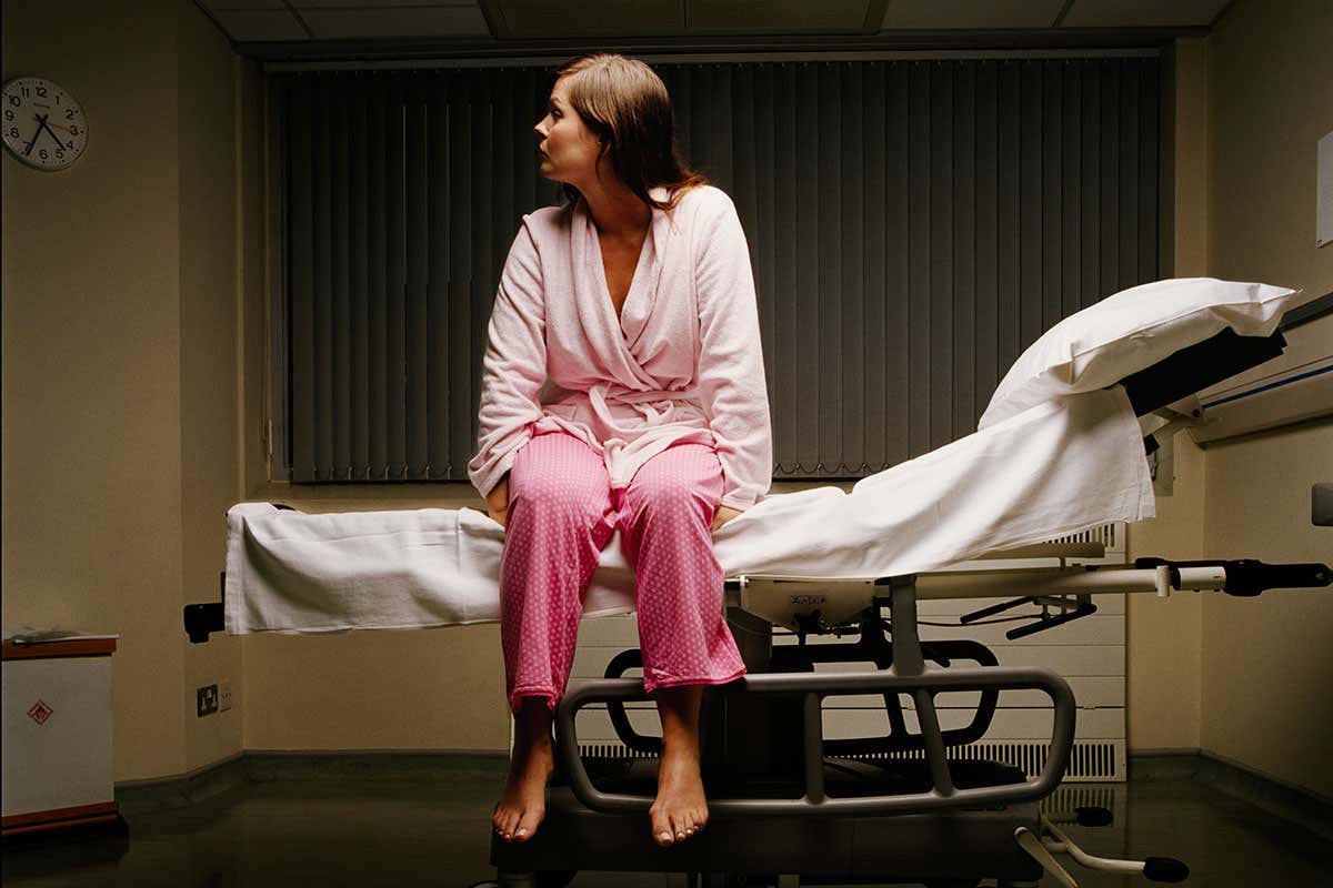 stock image of a woman sat on a hospital bed