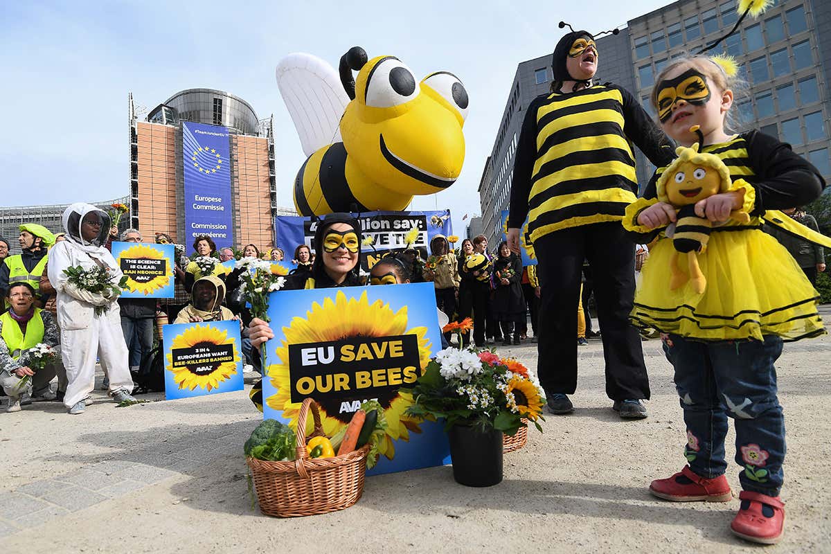 People in bee costumes hold signs such as 