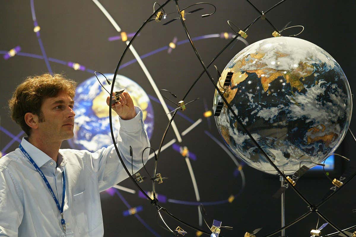 Man looks at globe surrounded by mini satellites mounted on metal arcs