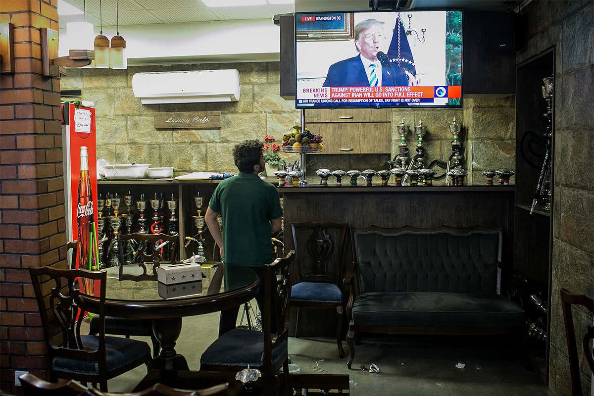 man watches Trump announcement on a TV in Iran
