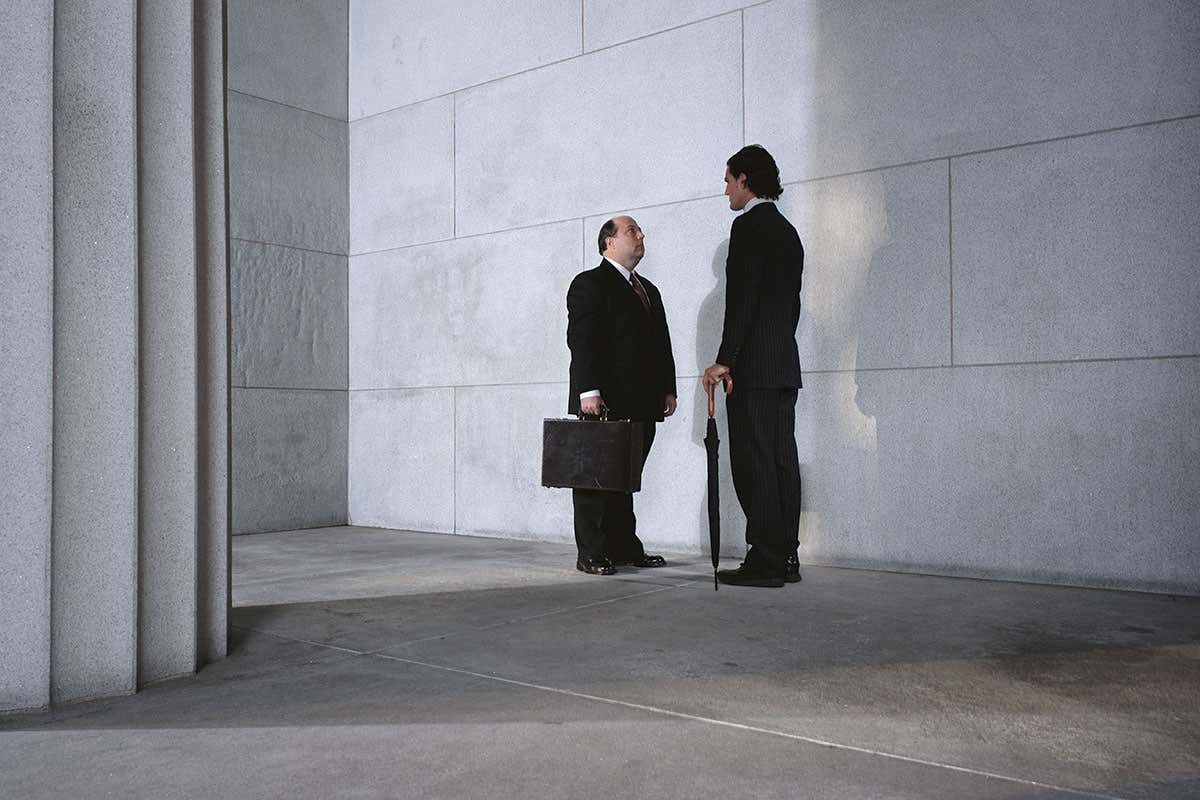 A shorter man talking to a taller man