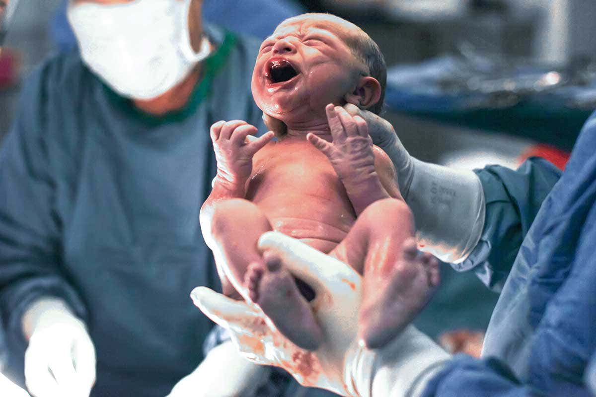 A newborn baby being held by a doctor
