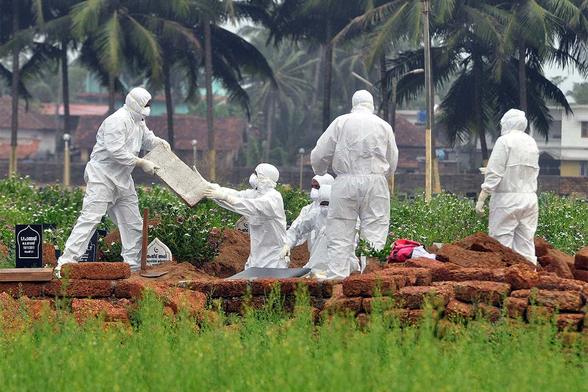 Doctors and relatives wearing protective gear dig a grave to bury the body of a victim of the Nipah virus
