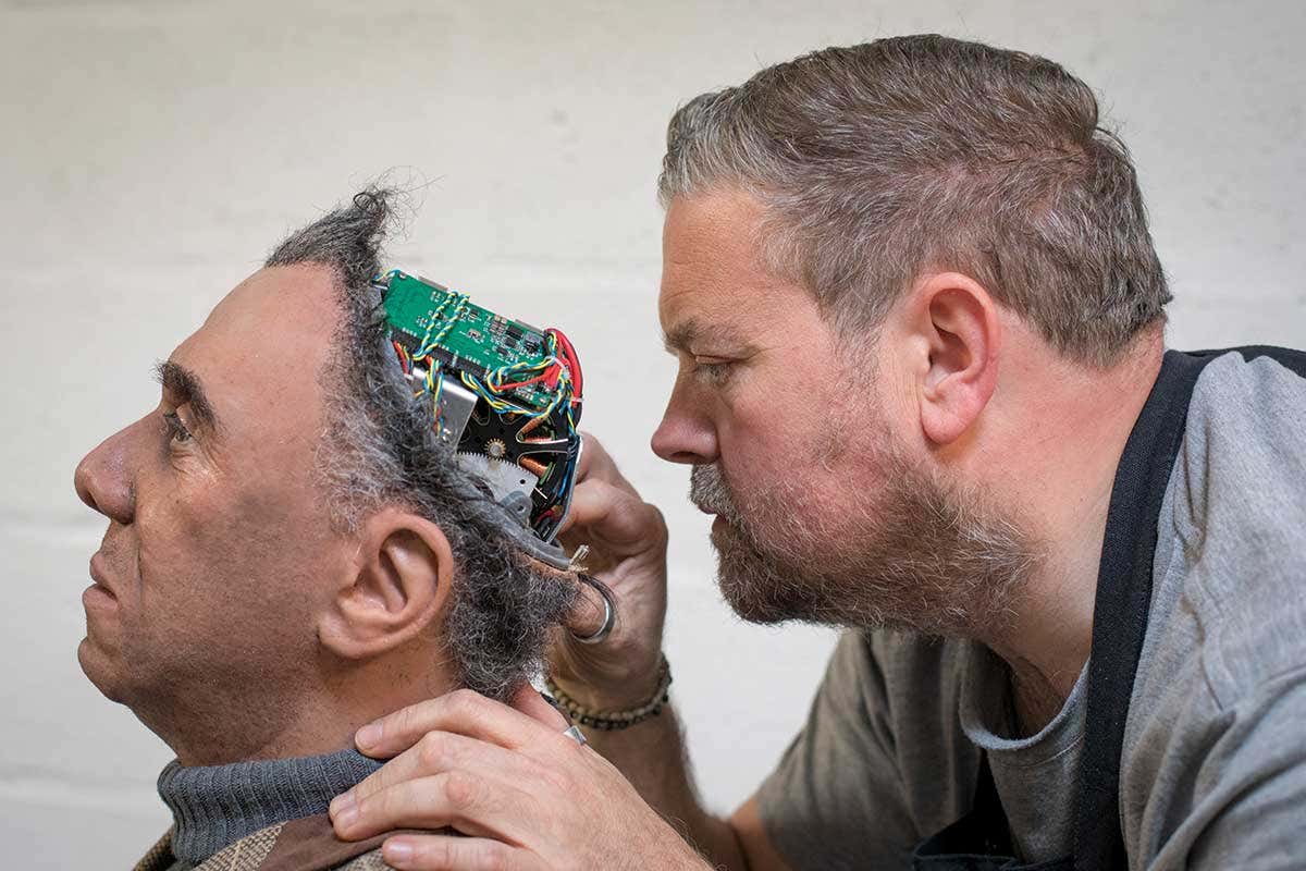 man reaching into robot's head