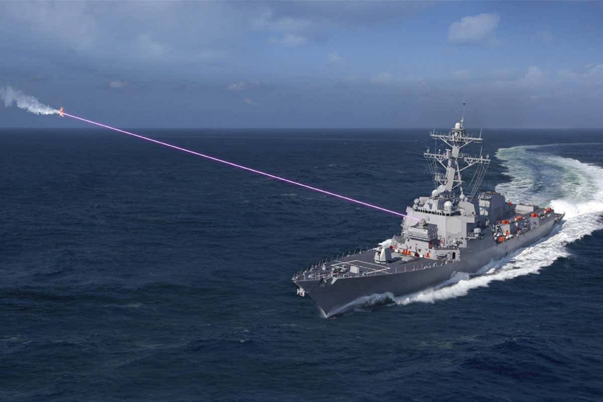 A large ship on the ocean firing a purple laser beam at a drone