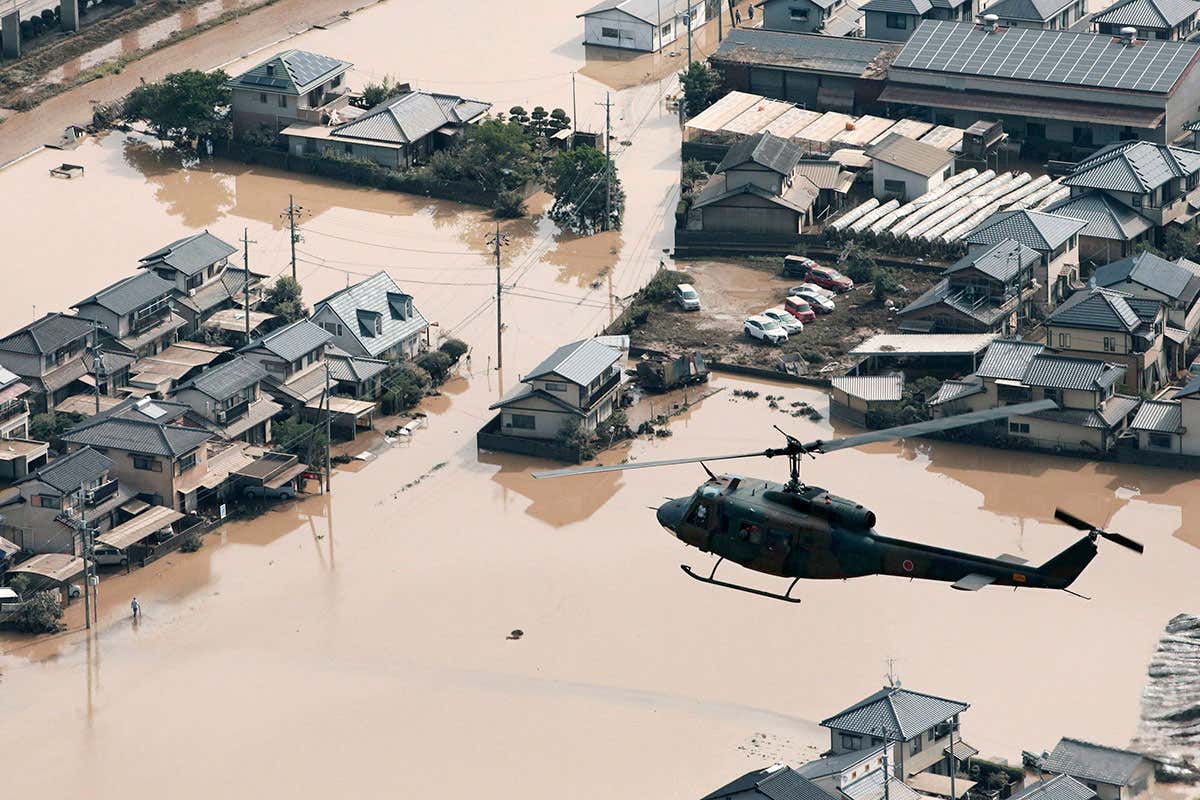 A helicopter flies over a flooded housing area in Kurashiki, Okayama prefecture