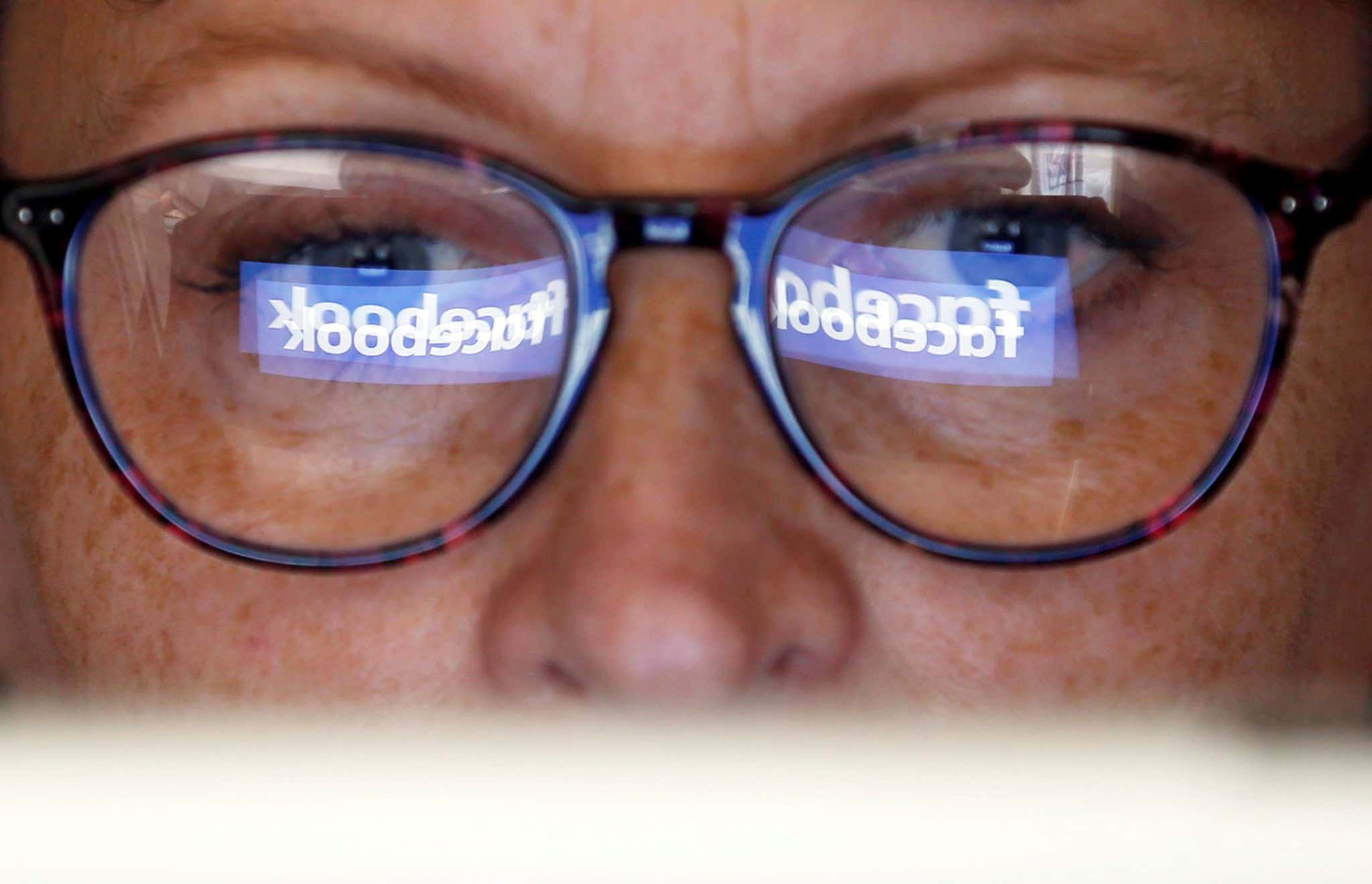 Facebook logo reflects in someone's glasses