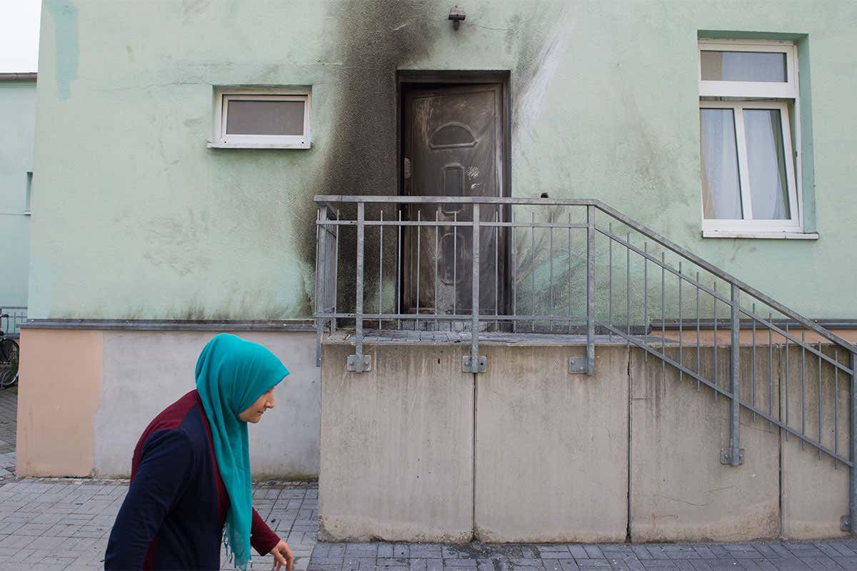A woman wearing a headscarf walks past the entrance to a mosque