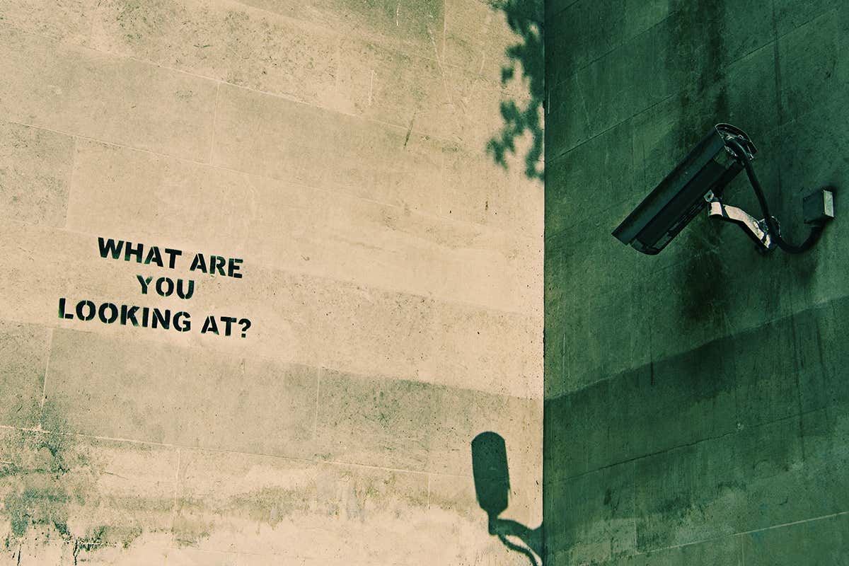 CCTV camera pointing at a wall with graffiti that reads 