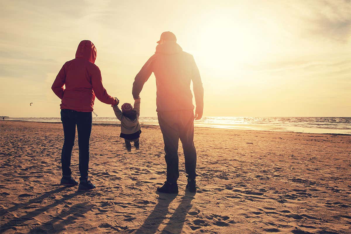 A child being held by parents looking into the sun