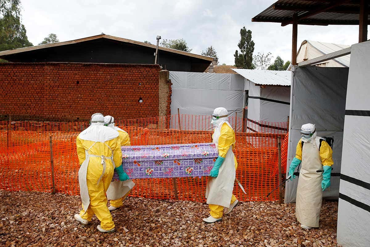 Health workers dressed in Ebola protective suits carry a coffin