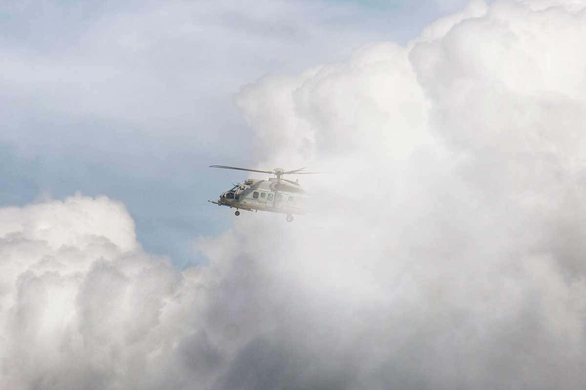 A helicopter passes by a cloud