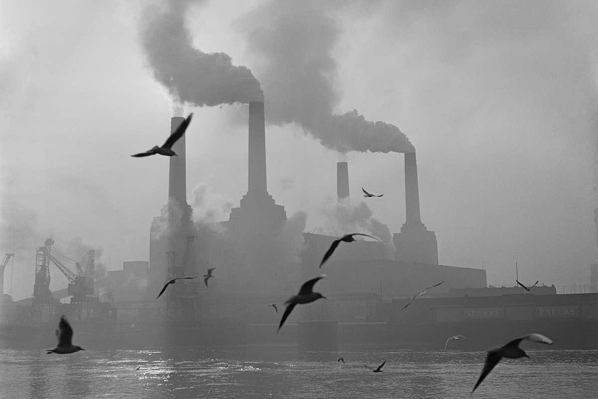 2nd February 1971: Seagulls drift above the waters of the Thames while in the background, the billowing chimneys of Battersea Power Station fill the sky.