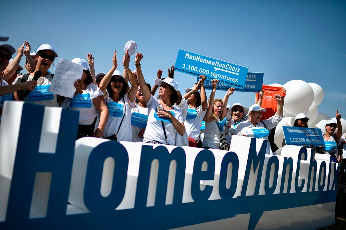People raise their hands and hold signs as they take part in a gathering called by the group 