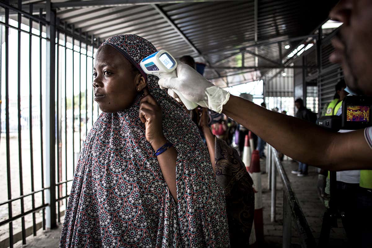 A woman gets her temperature measured at an Ebola screening station