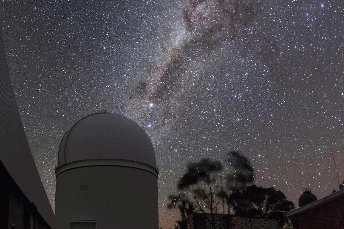 Telescope with milky way in the night sky above