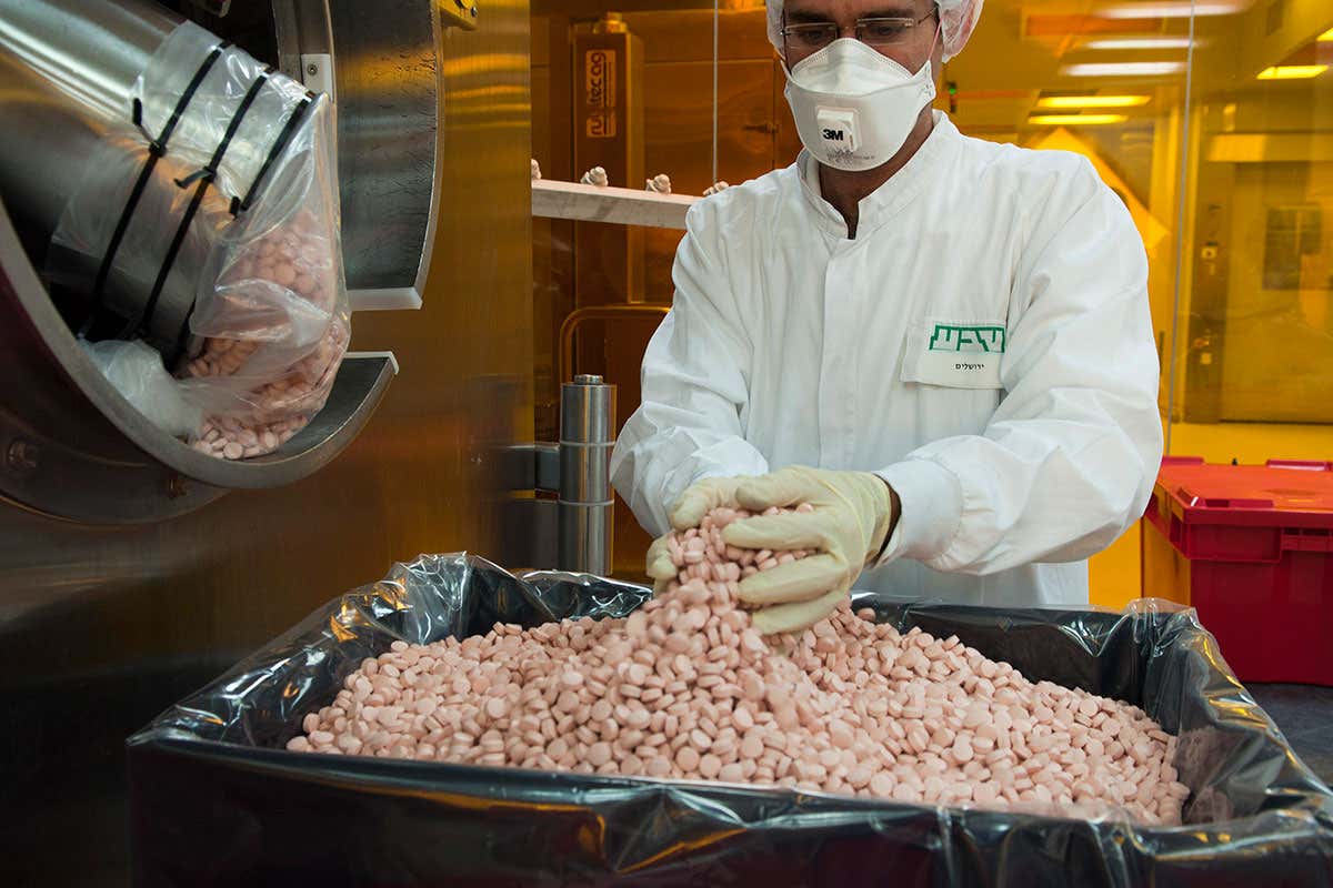 An employee collects newly-manufactured pills from a machine