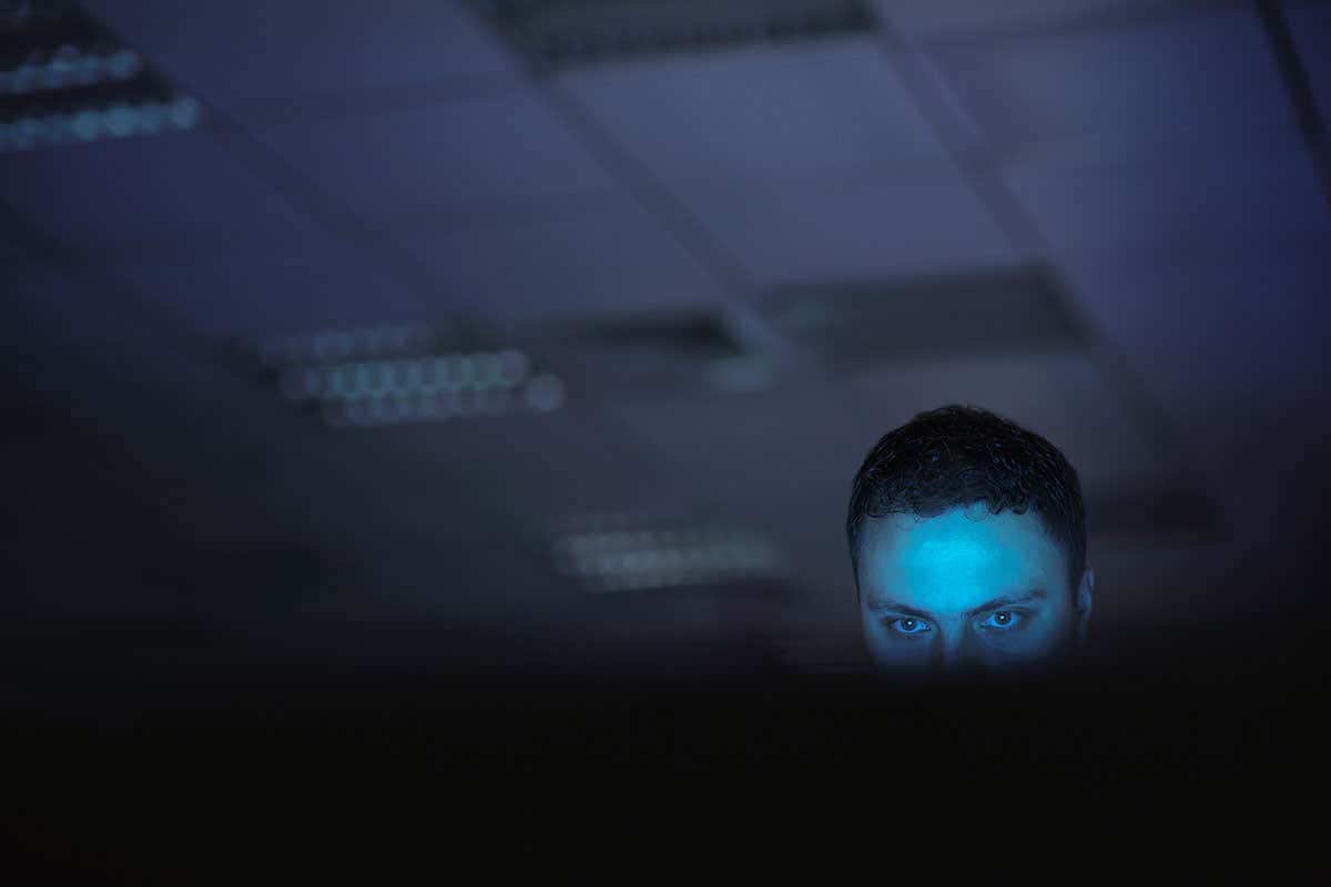 A man in a dark room looking at a screen