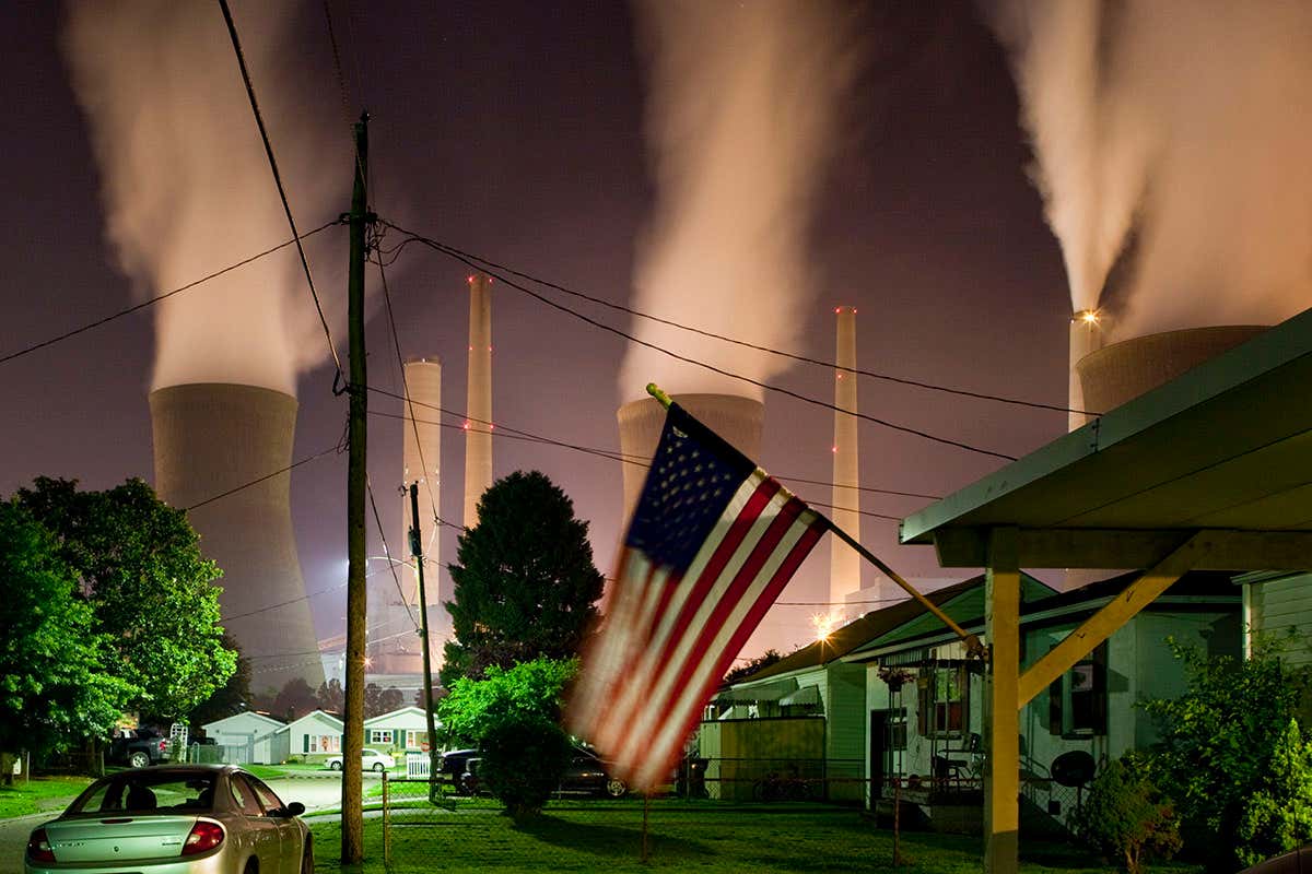 USA, West Virginia, Winfield, Steam billows from smokestacks at John Amos Coal-Fired Power Plant above neighborhood along Kanawha River on spring night