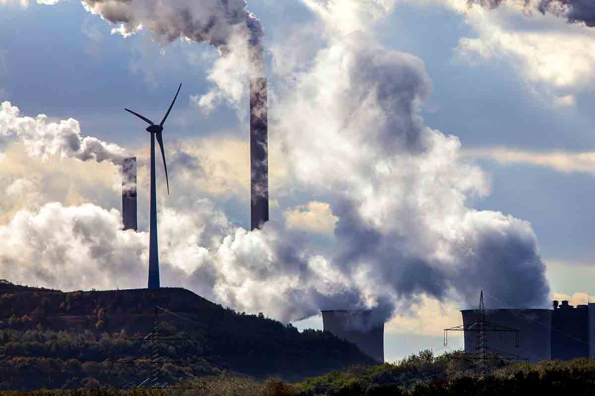 A picture of a wind turbine in front of a power station