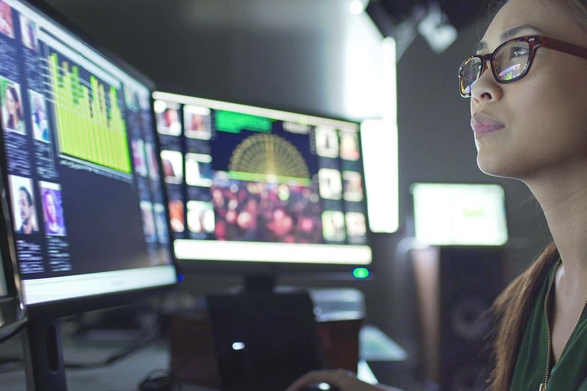 woman sitting at desk with computer screens