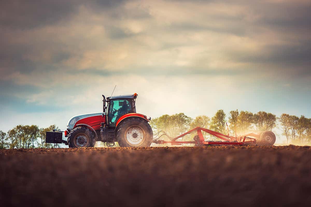 T59H63 Farmer in tractor preparing land with seedbed cultivator