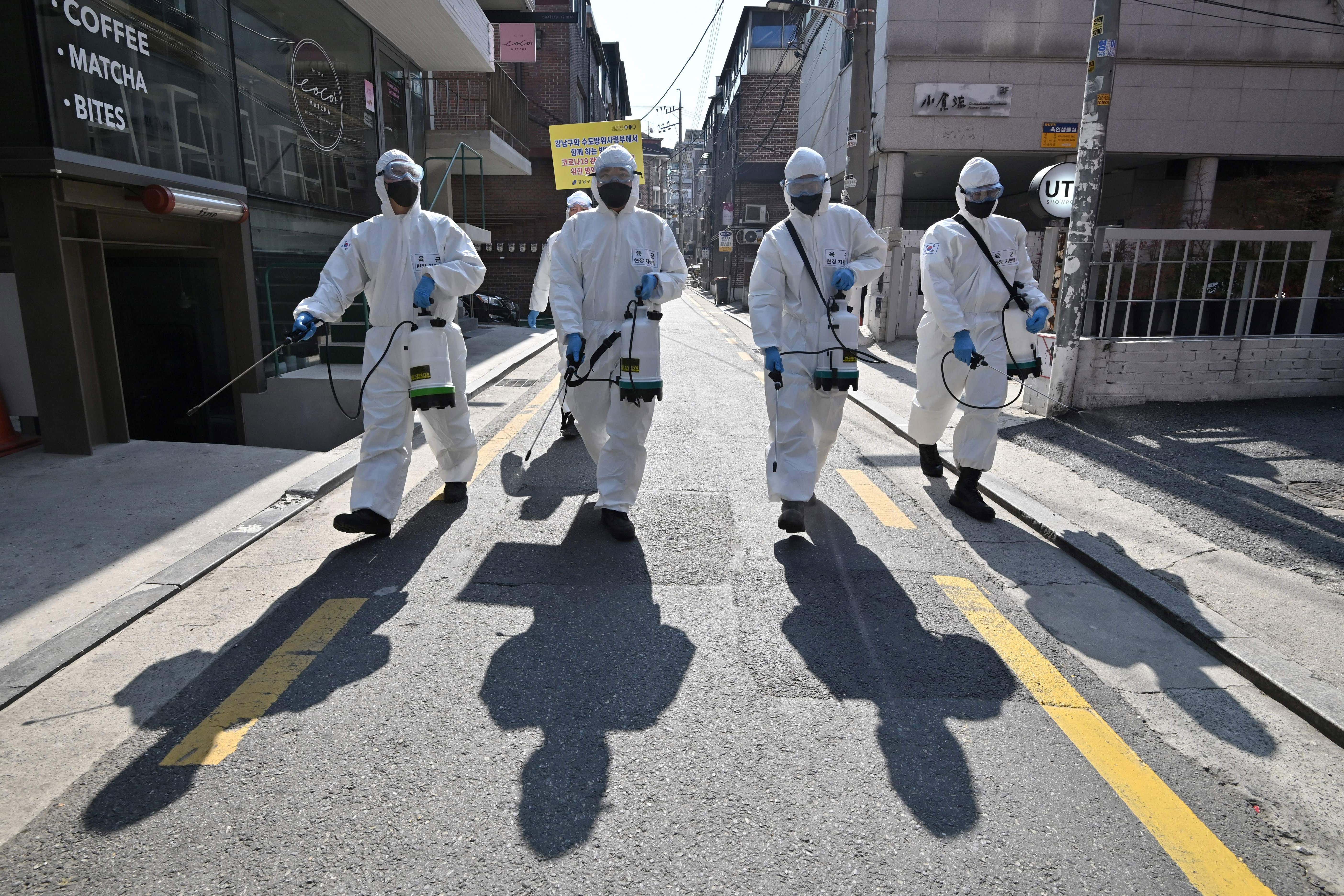 South Korean soldiers wearing protective gear spray disinfectant on the street to help prevent the spread of the covid-19 coronavirus